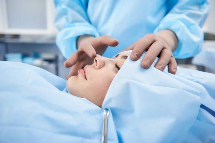 A young woman in an operating room undergoing rhinoplasty.