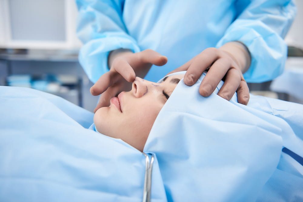 A young woman in an operating room undergoing rhinoplasty.