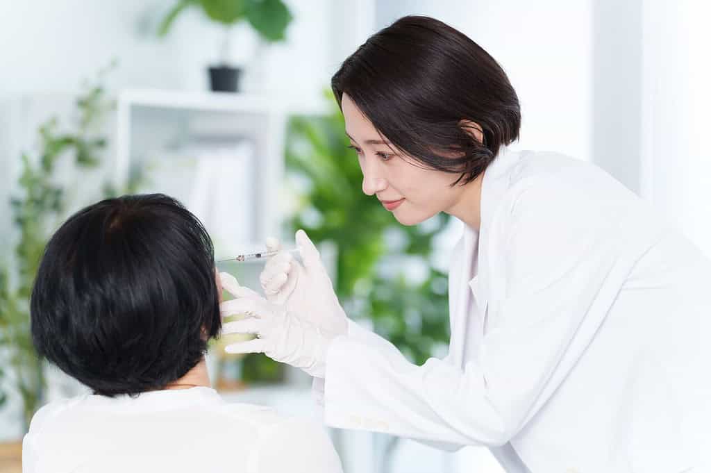 A dermatologist injecting a patient