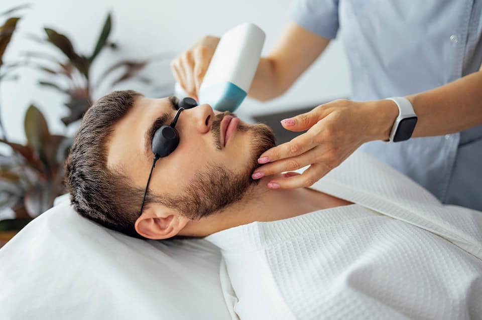 Professional female beautician doing male laser hair removal