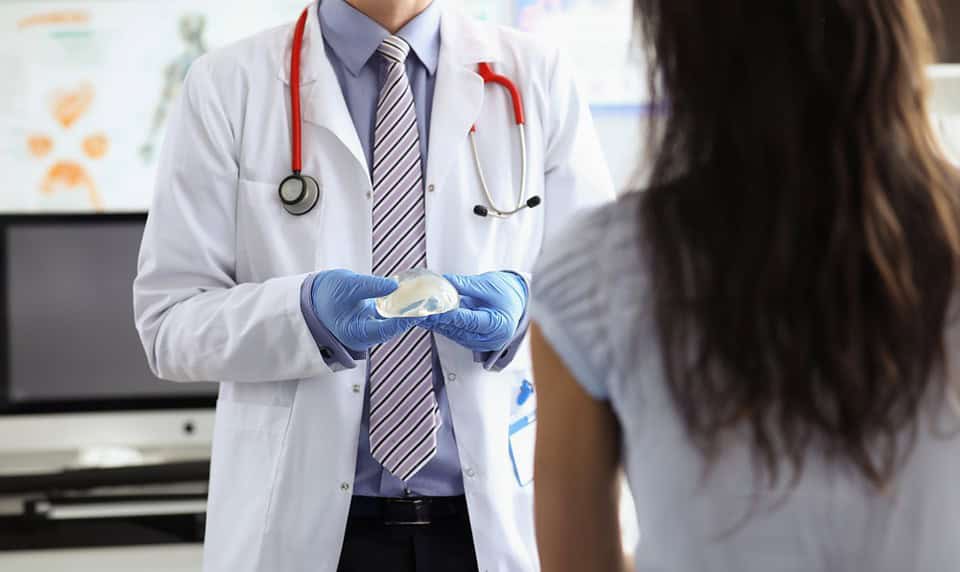 Plastic surgeon demonstrates a silicone implant to a patient