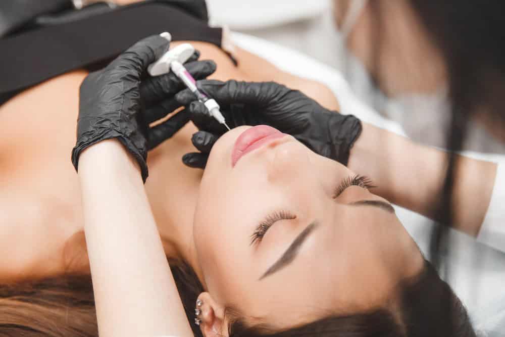 a clinician administers a filler injection into a patient’s chin