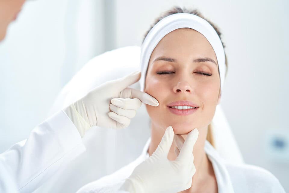 An esthetician checking a patient’s skin