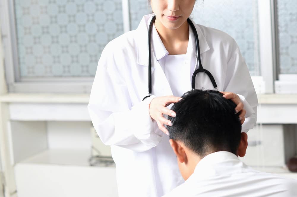 A doctor diagnoses a male patient’s hair condition to identify the ideal thinning hair treatment.