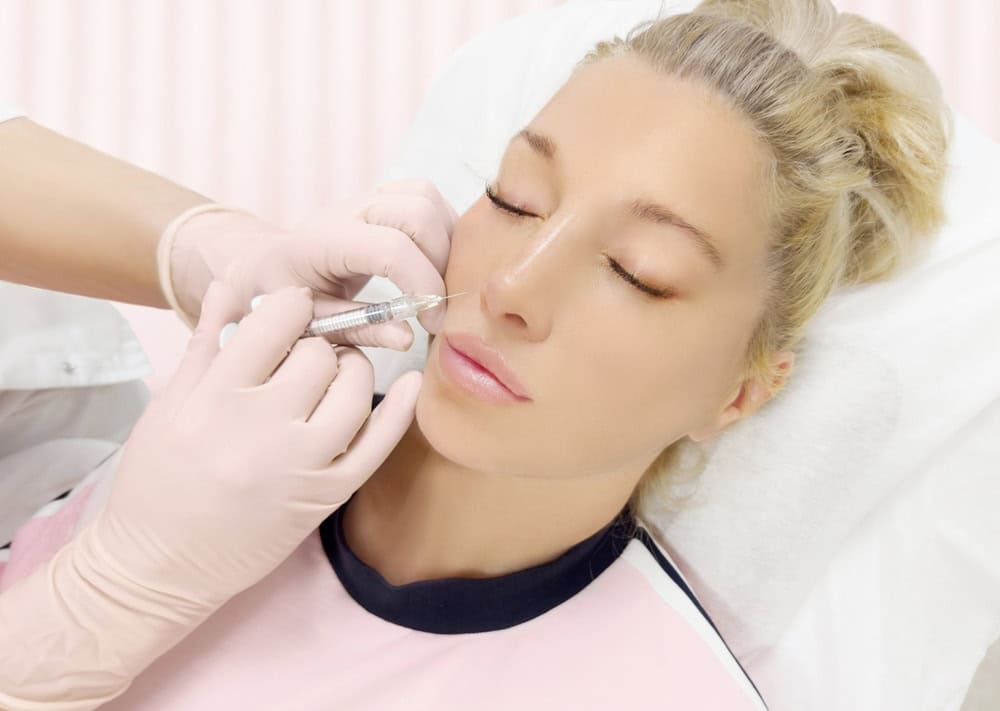 Woman receiving a filler injection at the corner of her mouth to address marionette lines