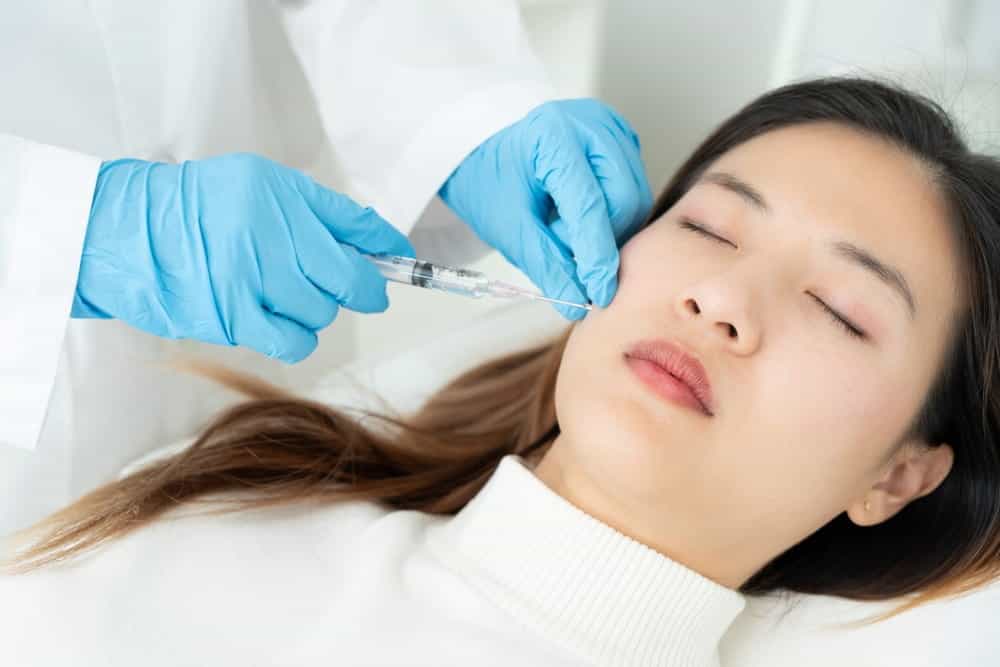 A doctor administers a Restylane filler to a female patient’s face.