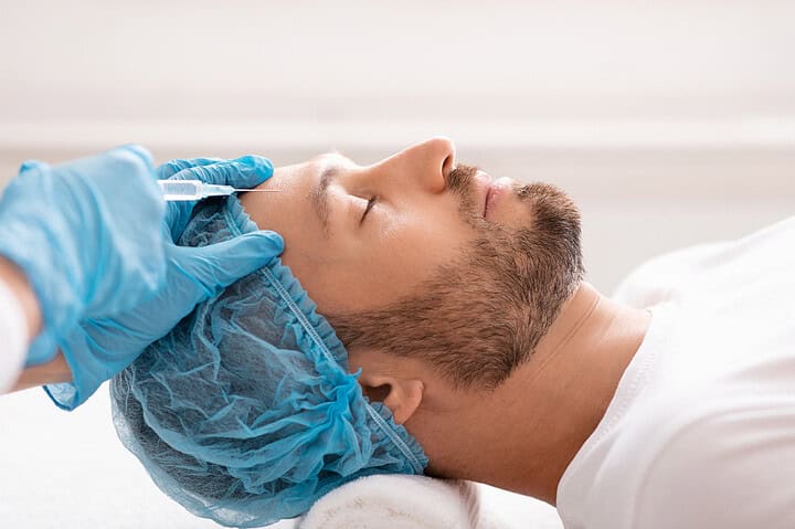 A dermatologist carefully carrying out a male forehead filler treatment
