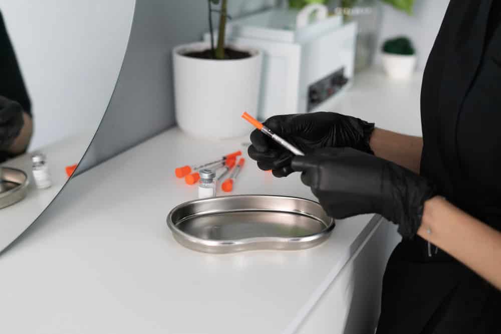 Cosmetologist organizing syringes and a vial in a tray prepared for botox units per area treatment