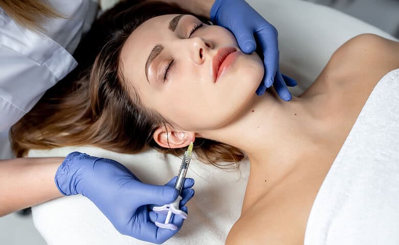 A cosmetic doctor preparing to administer Botox to a female patient's lower face.