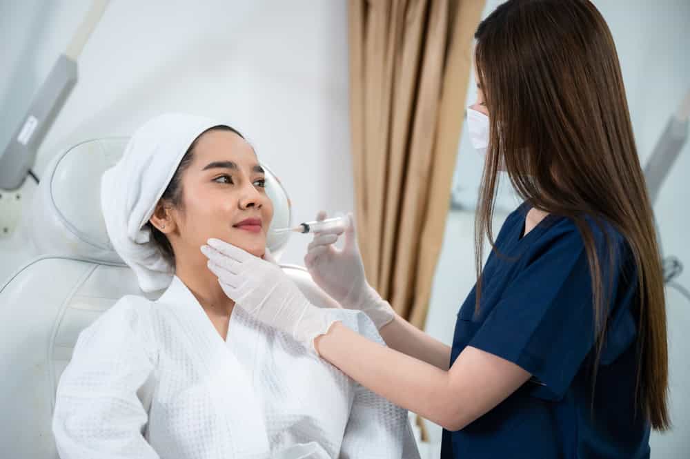 A cosmetic doctor administering a Botox injection to a patient’s lip lines, one of several sites. 
