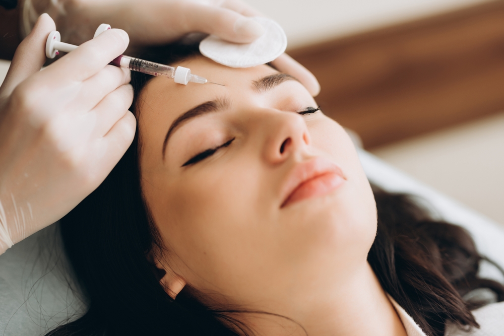 A cosmetic doctor administering an Allergan Botox injection to the forehead of a female patient.
