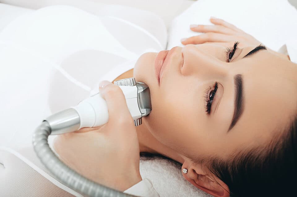 A beautician performing face lift muscle tightening via a non-surgical route.
