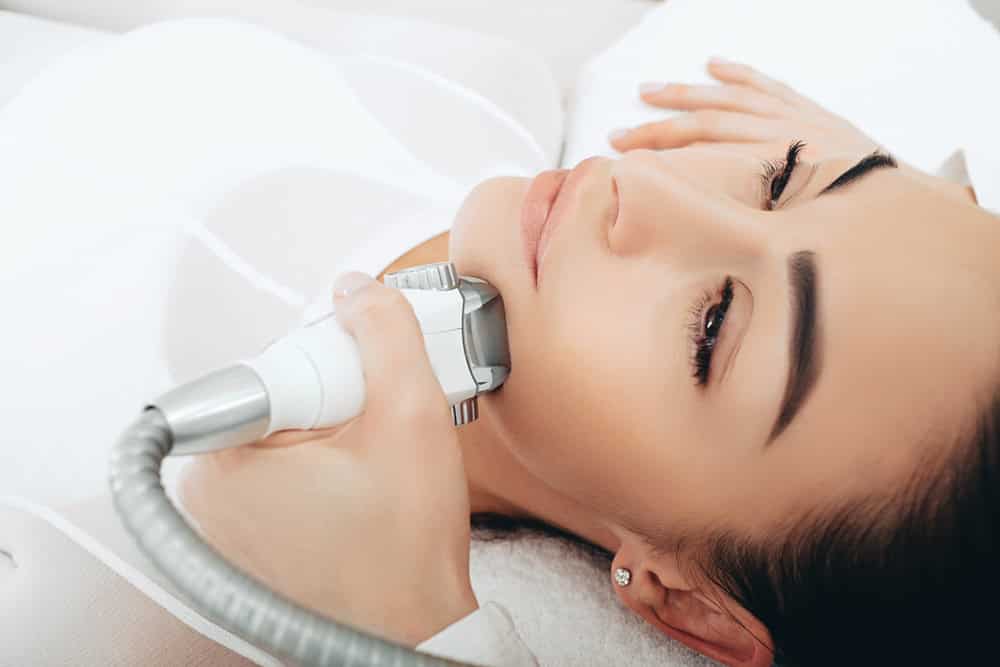 A beautician performing face lift muscle tightening via a non-surgical route.
