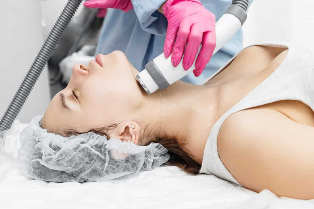 A dermatologist administering a non-surgical skin tightening procedure to a young woman.